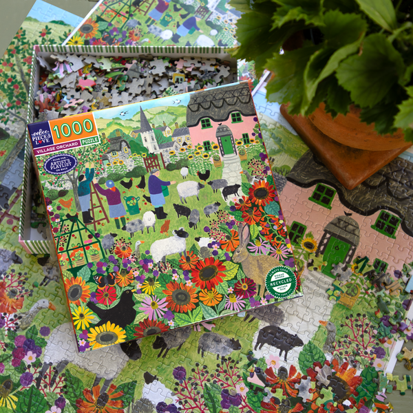 Jigsaw puzzle box with a colorful village scene on a partially completed puzzle.
