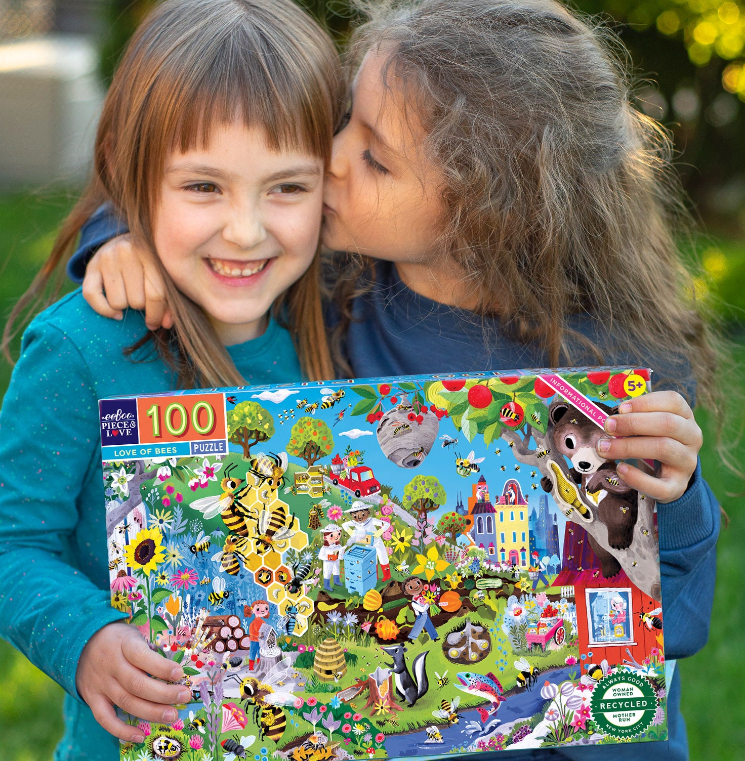 Two young girls showing affection while holding a puzzle box