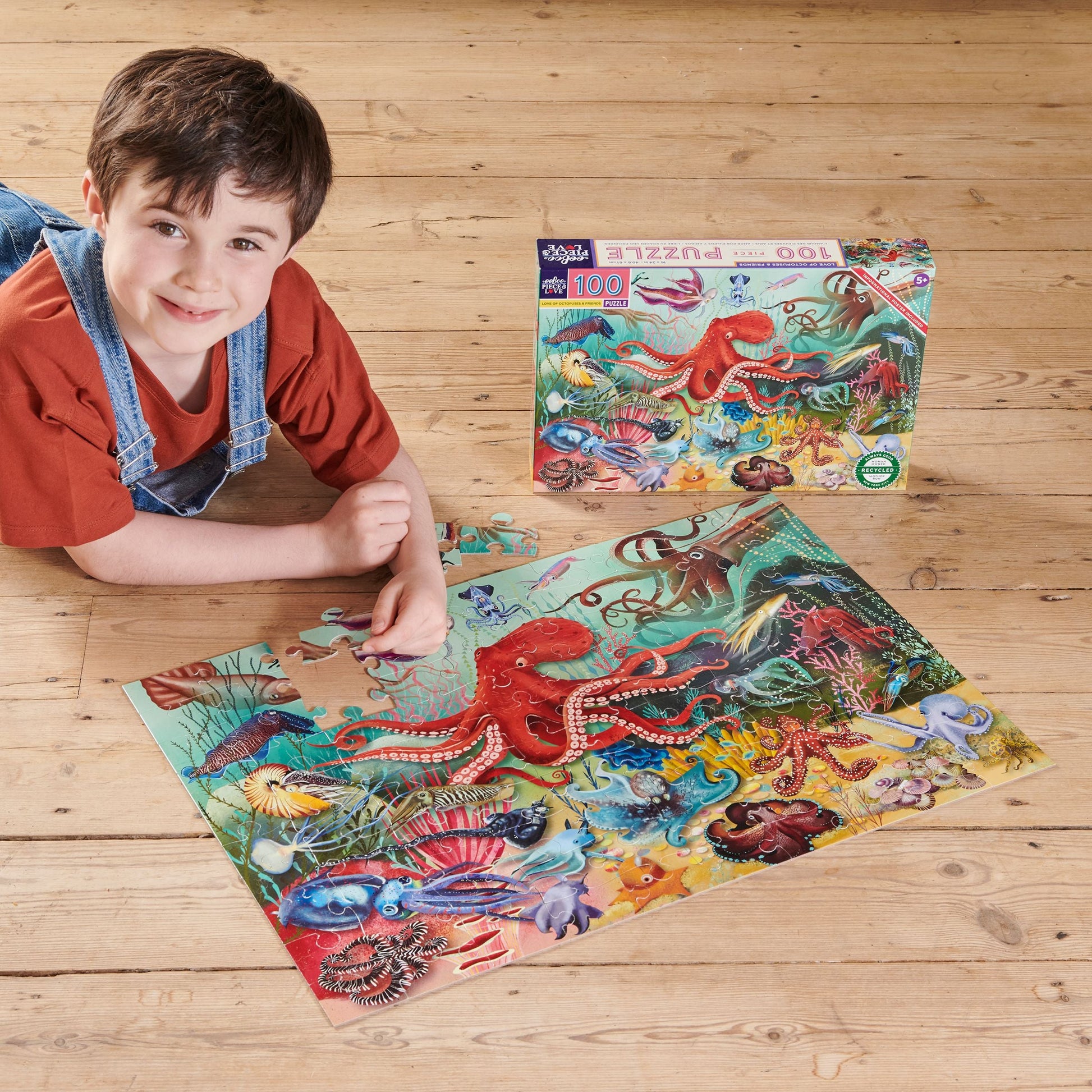 Child playing with puzzle of various sea creatures including an octopus on a colorful underwater background.