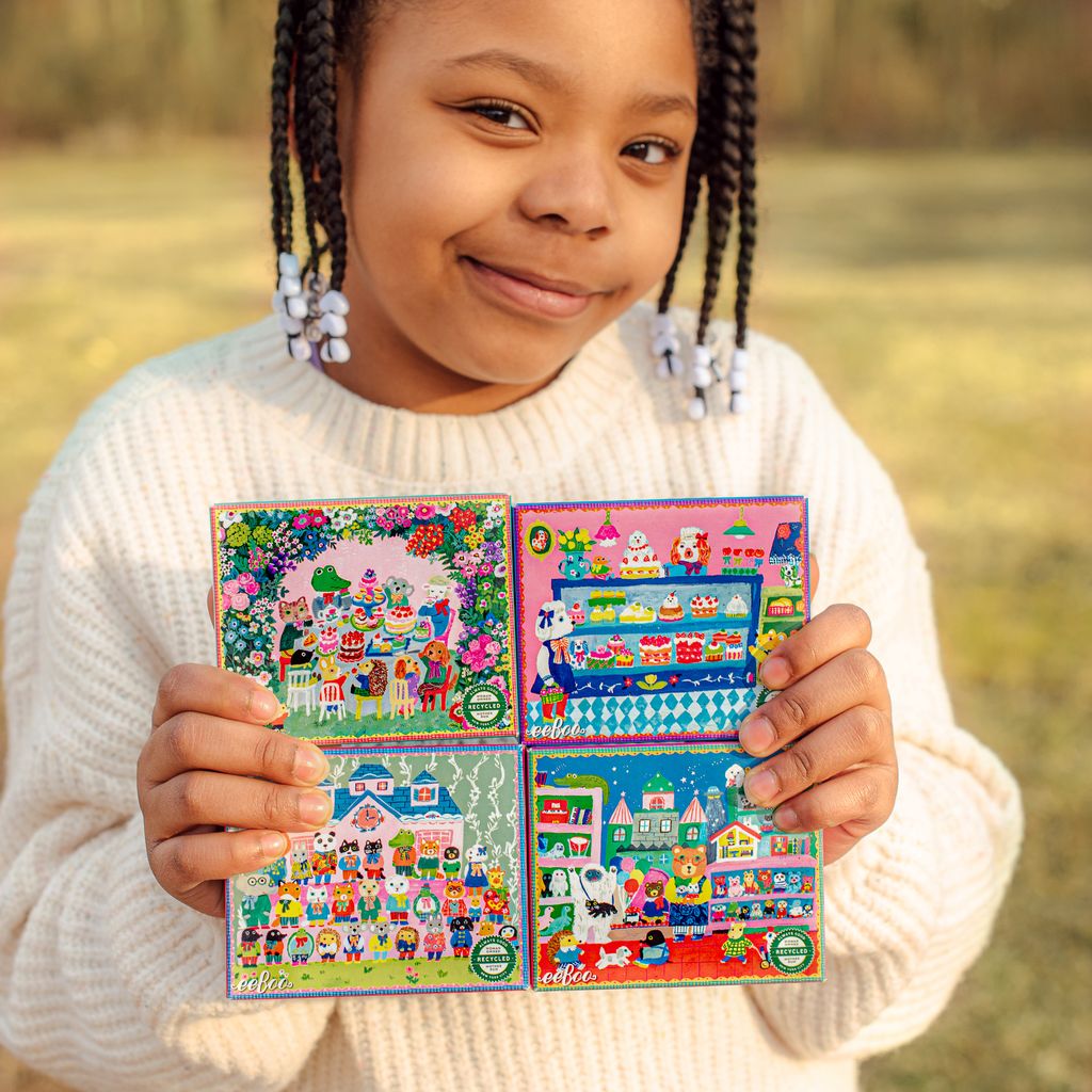Child holding four small puzzle boxes and smiling. yumis-mini-puzzle-assortment-16
