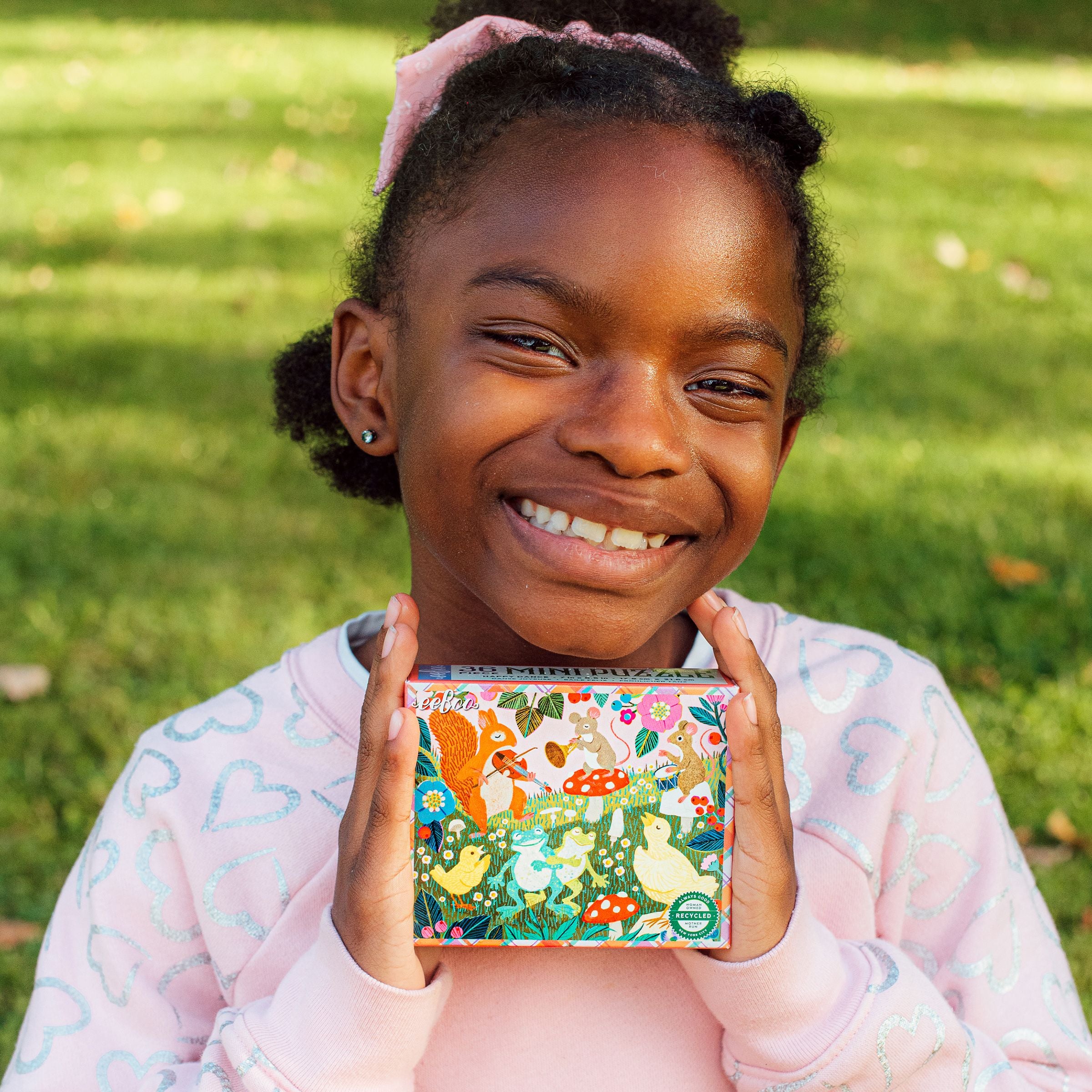Young girl in a pink sweater holding a mini puzzle