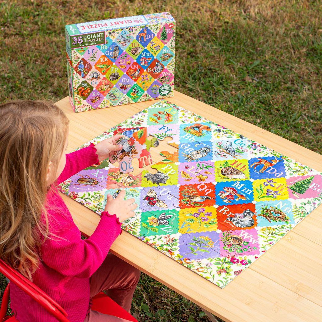 Child playing with a colorful A is for Acorn 36 Piece Giant Alphabet Puzzle on a wooden table outdoors