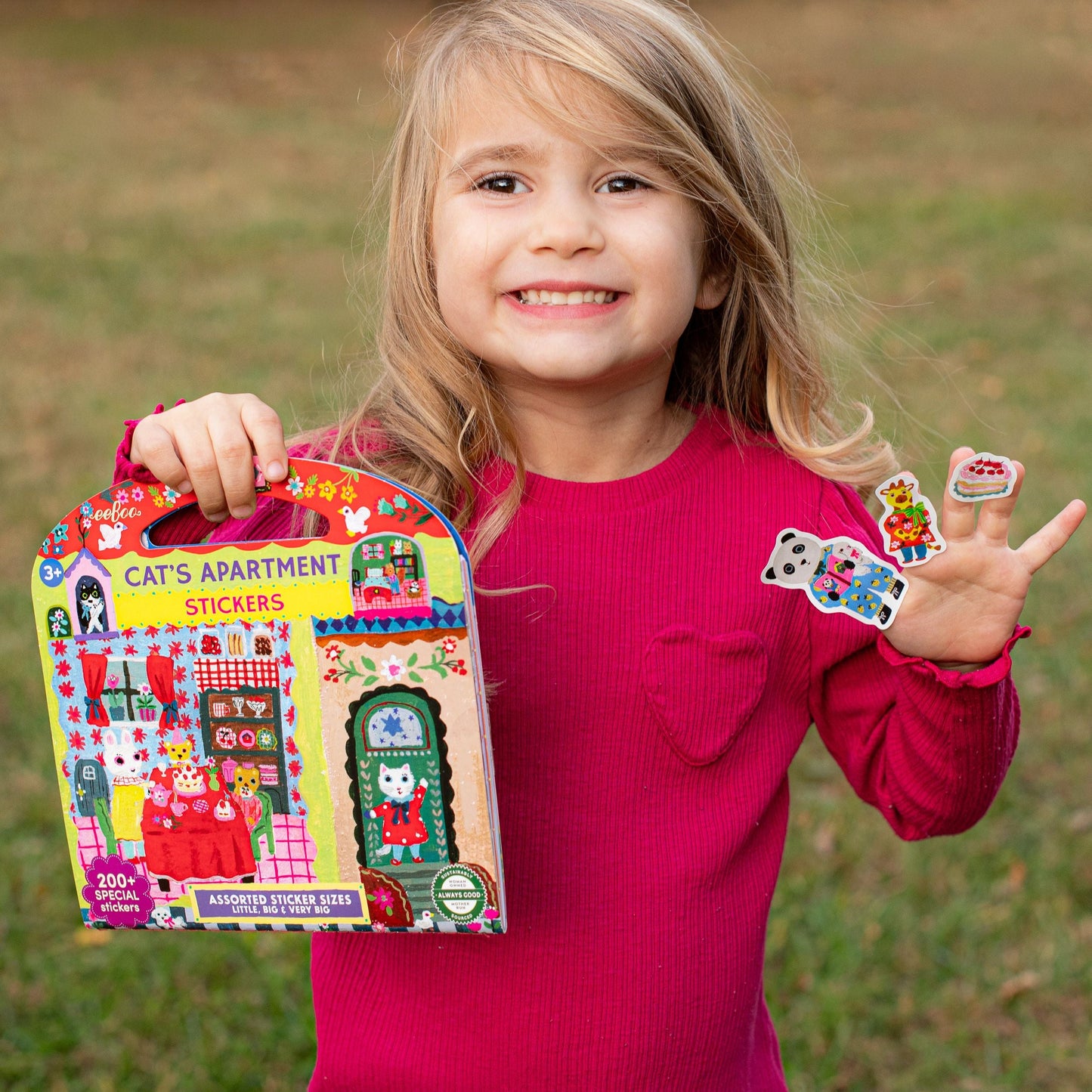 Child holding a sticker book and stickers outdoors