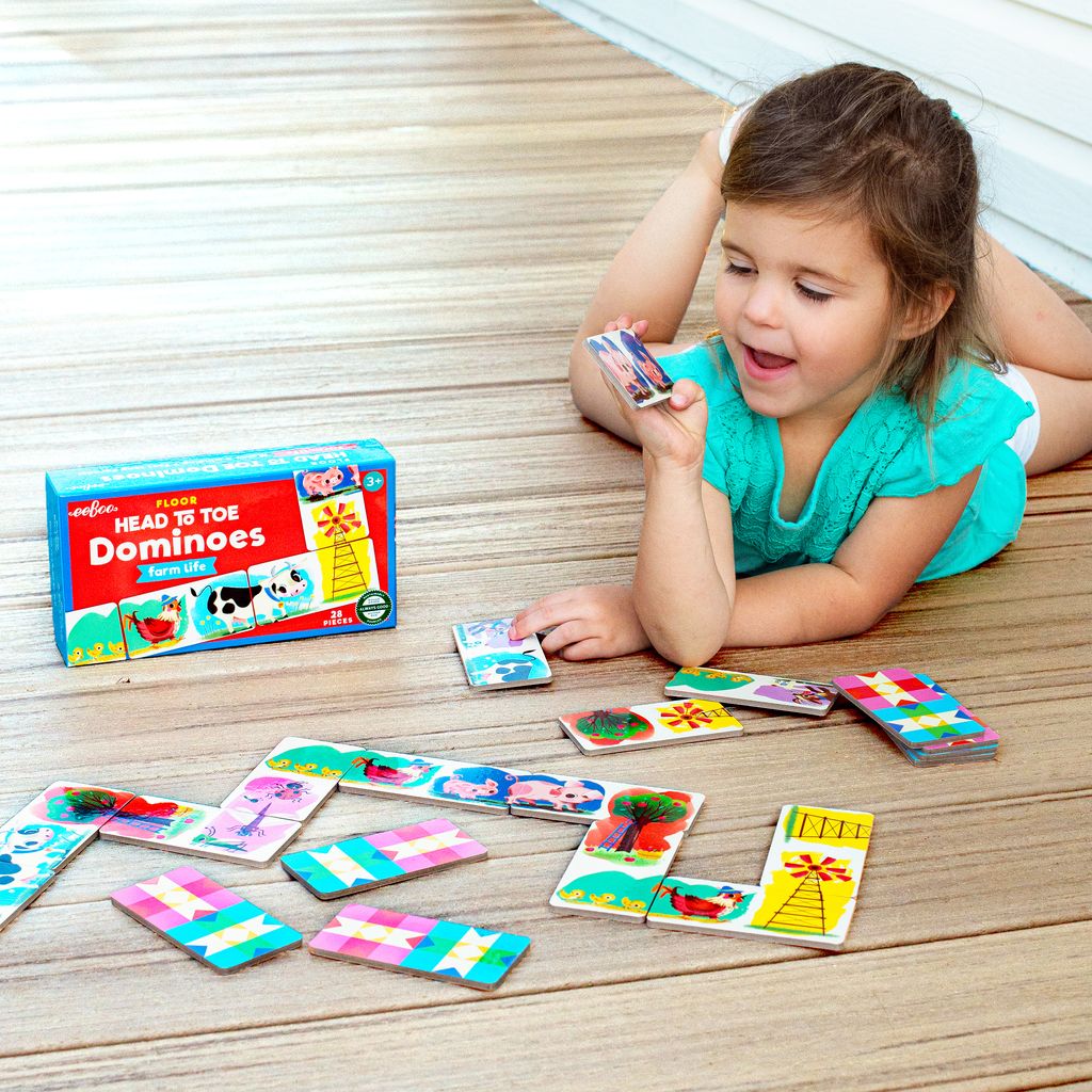 Child playing with colorful dominoes on a wooden floor. Little Farm Head to Toe Dominoes