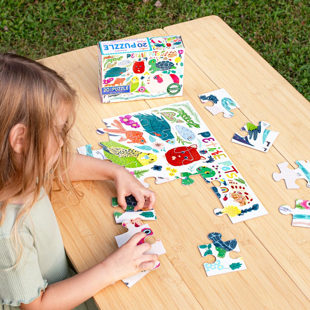 Child playing with a puzzle on a wooden table outdoors. Petite Pets 20 Piece Puzzle