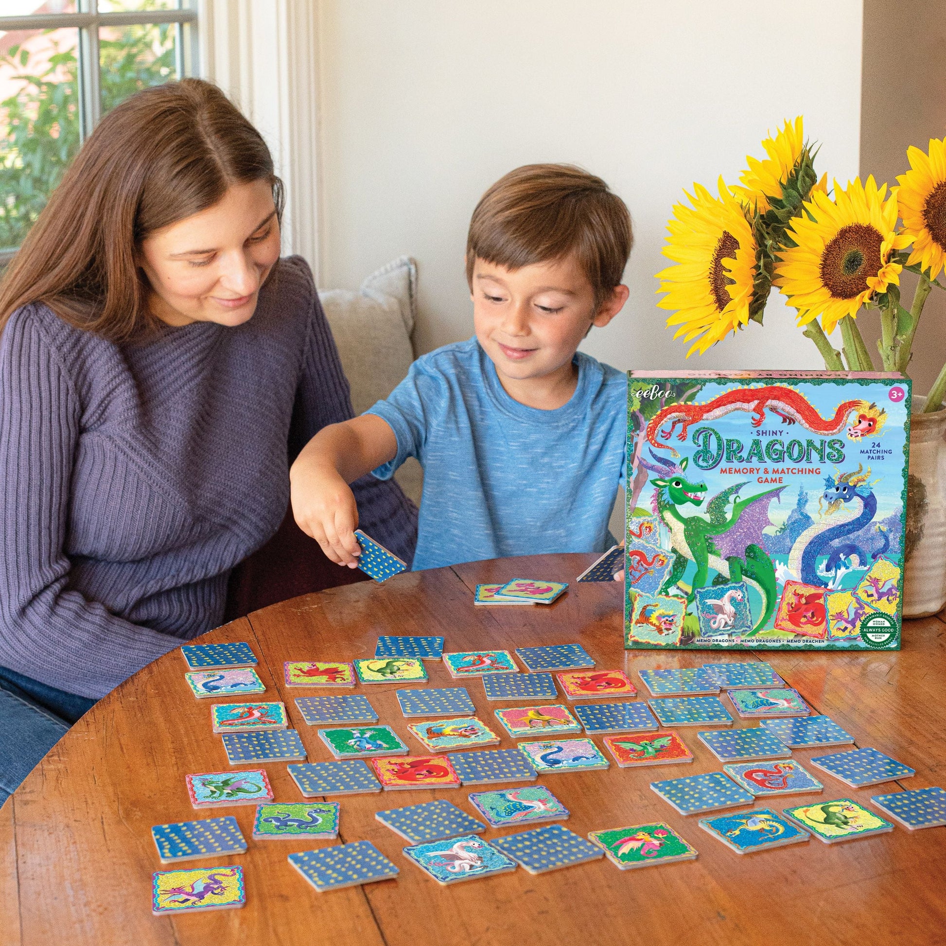 Woman and child playing a board game with colorful game pieces on a wooden table.