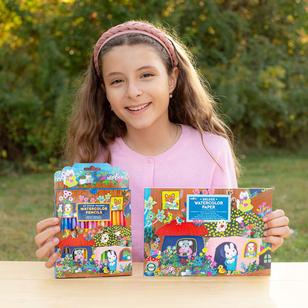 Girl holding packages of watercolor pencils and paper outdoors